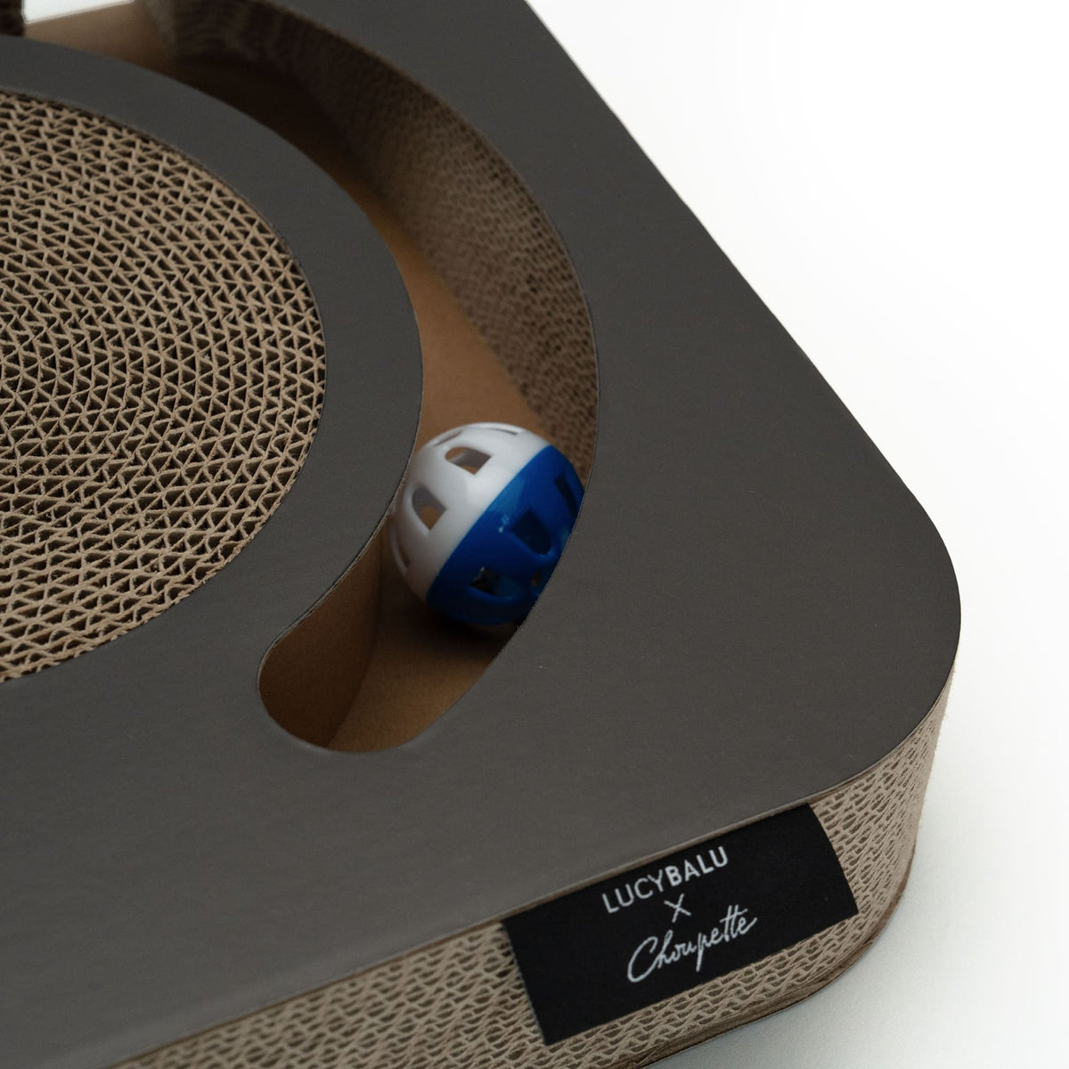 Detailaufnahme: Integrierte Spielbahn mit Glöckchen-Ball und Kratzfläche aus Wellpappe.