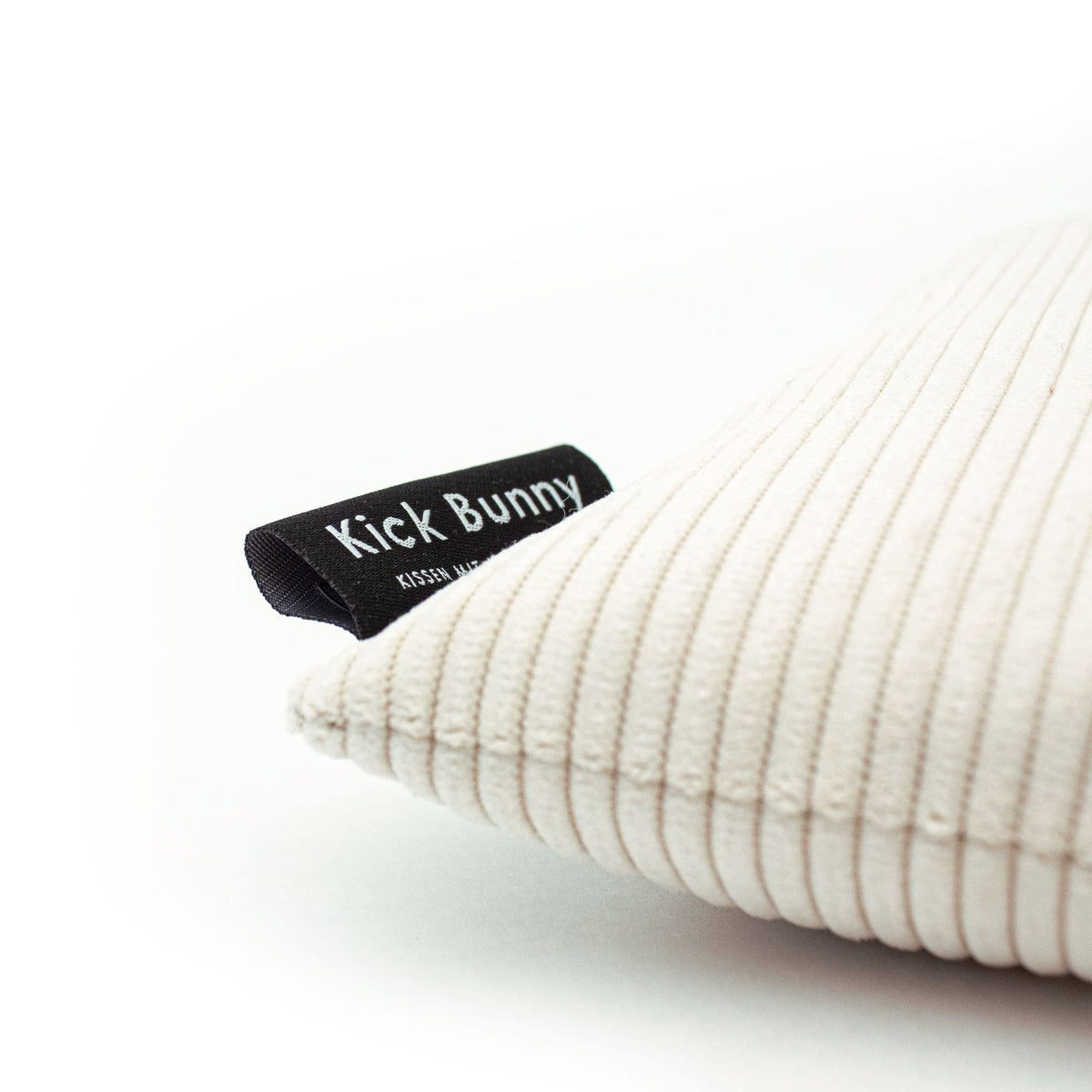 Seitliche Detailansicht eines weißen Cord Bunny Kick Kissens mit eingenähtem LucyBalu Etikett