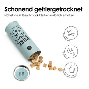 Umgekippte Dose mit der Aufschrift „Pure Snack for Cats – 100 % Duck“, aus der würfelförmige gefriergetrocknete Katzenleckerlis herausfallen, daneben Symbolgrafiken.